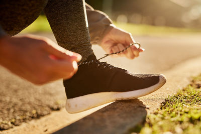 Low section of man tying shoelace