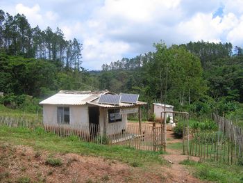 Houses on field by trees against sky