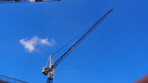 Low angle view of cranes against blue sky