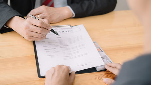 Midsection of man holding paper with text on table