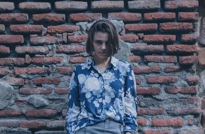 Young woman standing against brick wall