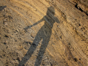 High angle view of shadow on dirt road