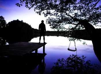 Silhouette man by lake against sky