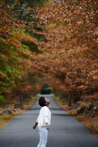 Rear view of woman standing on footpath during autumn