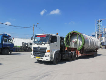 Vehicles on road against blue sky