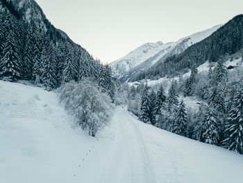 Snow covered road by mountains against sky