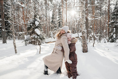 Mother and daughter playing in the winter sunny forest. high quality photo