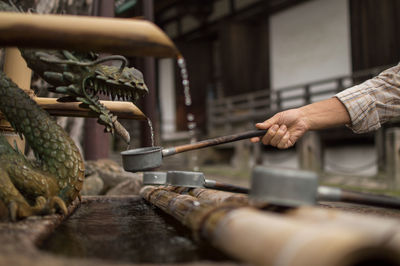 Midsection of person preparing meat on barbecue grill