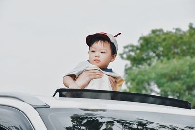 Boy looking away against car