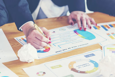 Midsection of businesswoman writing on paper at desk in office