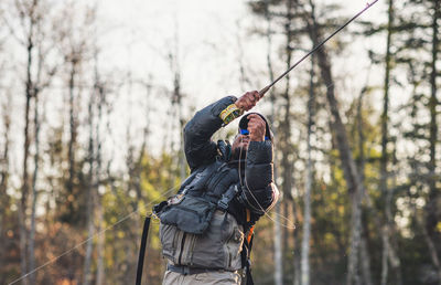 Low angle view of man holding umbrella in forest