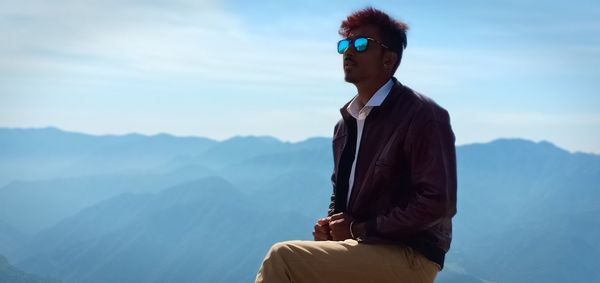 Man wearing sunglasses while standing against sky