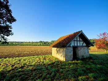 House on field against clear blue sky