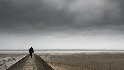 Rear view of woman walking on calm beach