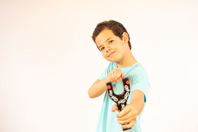 Portrait of boy holding camera over white background