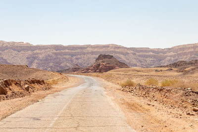 Road amidst desert against clear sky