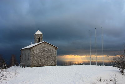 Building on field against sky during winter