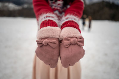 Midsection of woman showing gloves while standing on land during winter