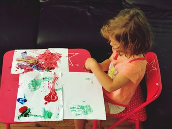 High angle view of girl painting on paper at home