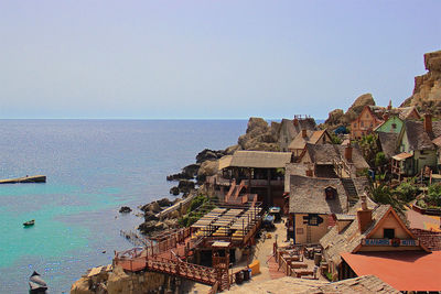 High angle view of buildings by sea against clear sky