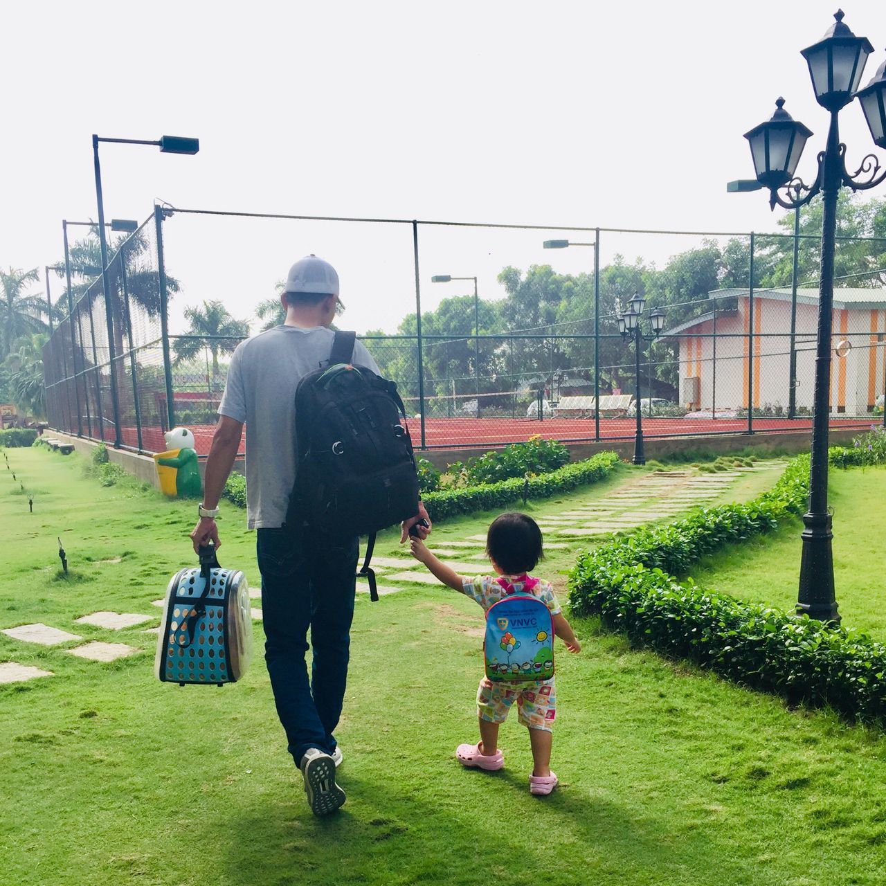 REAR VIEW OF MOTHER AND SON WALKING ON GRASSLAND