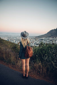 Rear view of woman standing by sea against clear sky