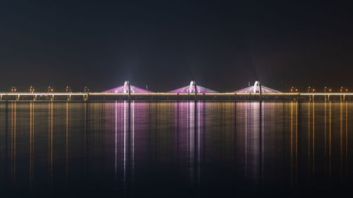 Illuminated bridge over river at night