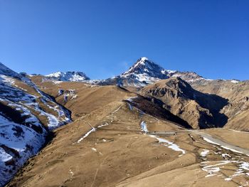 Scenic view of snowcapped mountains against clear blue sky