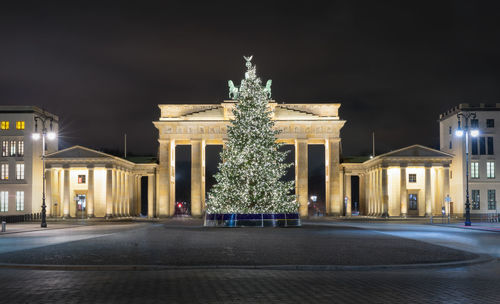 Illuminated christmas tree against brandenburg gate at night