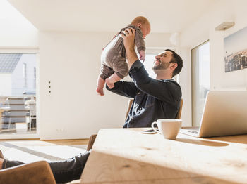 Father sitting at home playing with baby son