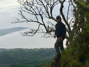 Man on tree mountain against sky