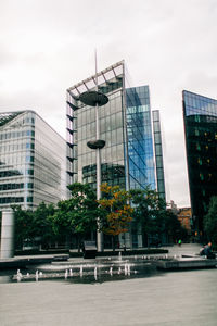 Modern buildings by street against sky in city