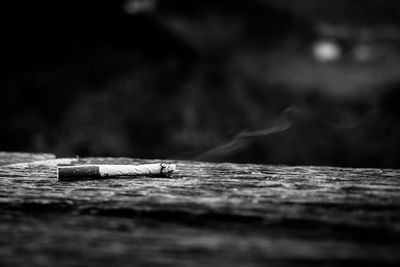 Close-up of lit cigarette on wood