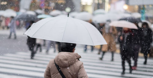 Reflection of woman on wet umbrella in city