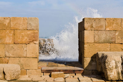 Sea waves splashing on rocks against wall