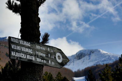 Information sign on snow covered mountain against sky