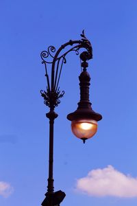 Low angle view of illuminated street light against blue sky