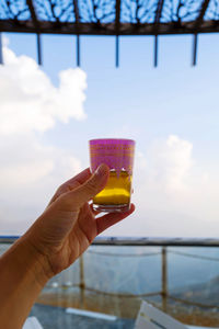 Hand holding moroccan tea in traditional tea cup against the clouds