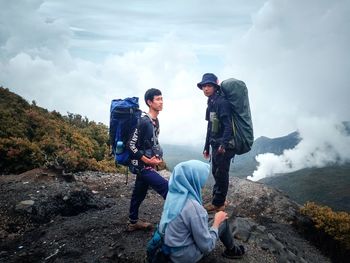 Friends on mountain against sky