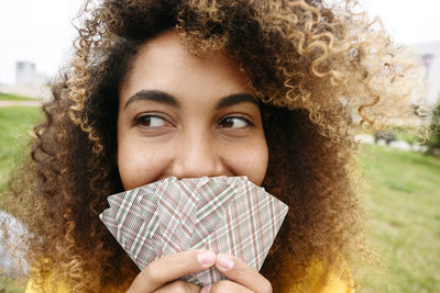 Young woman covering mouth with playing cards