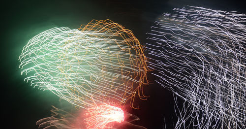 Illuminated firework display against sky at night