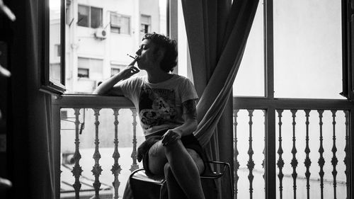 Rear view of young woman standing by window
