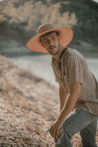 Portrait of man wearing hat while standing on land