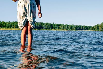 Low section of person standing on shore against sky