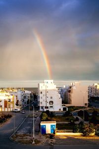 Rainbow over road against buildings in city