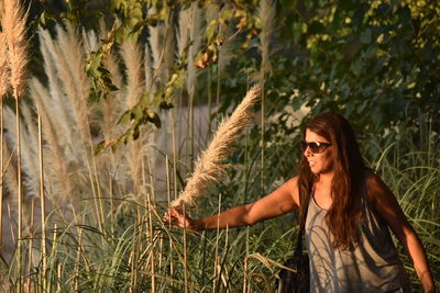 Woman holding plant while standing on grassy field