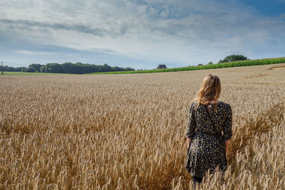 Rear view of woman standing on field against sky