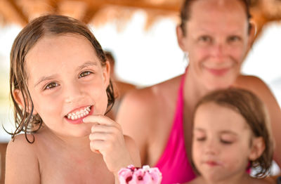 Close-up portrait of shirtless girl clenching teeth by family at beach