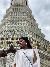 Young woman standing outside temple against building