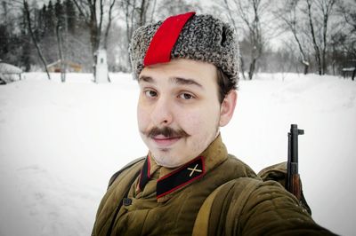 Close-up portrait of smiling army soldier standing in snow